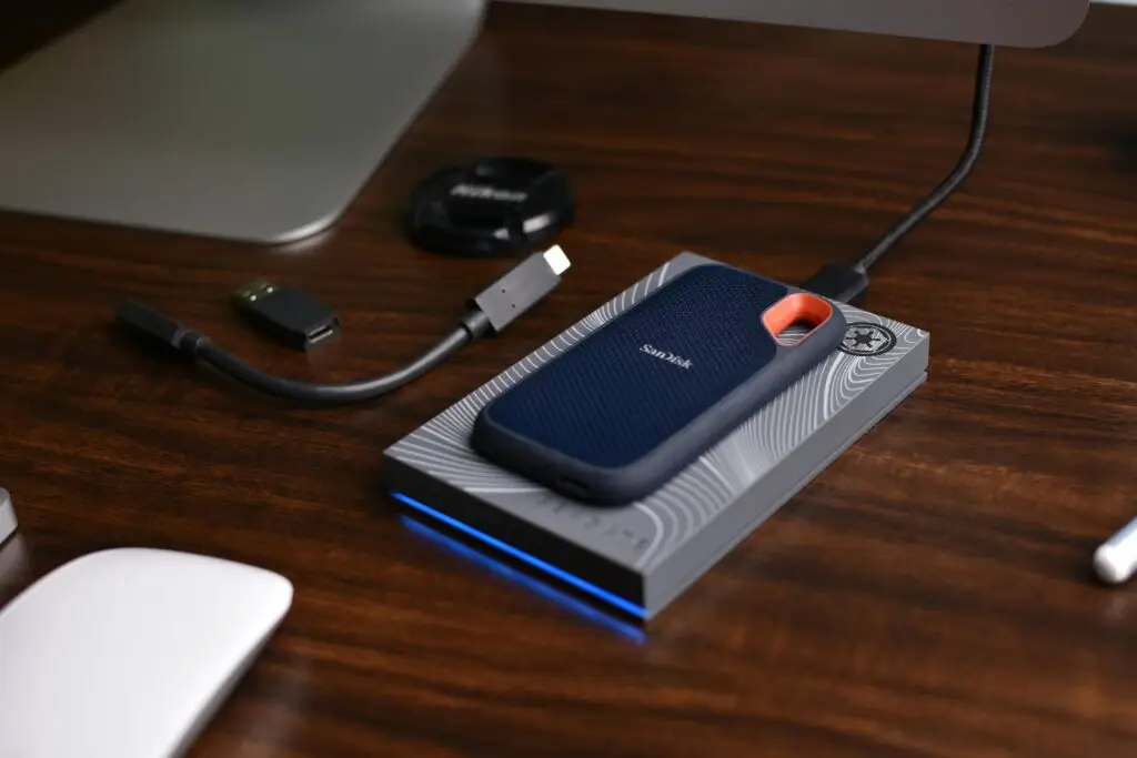 A SanDisk SSD with USB accessories on a wooden desk, showcasing portable technology storage solutions.